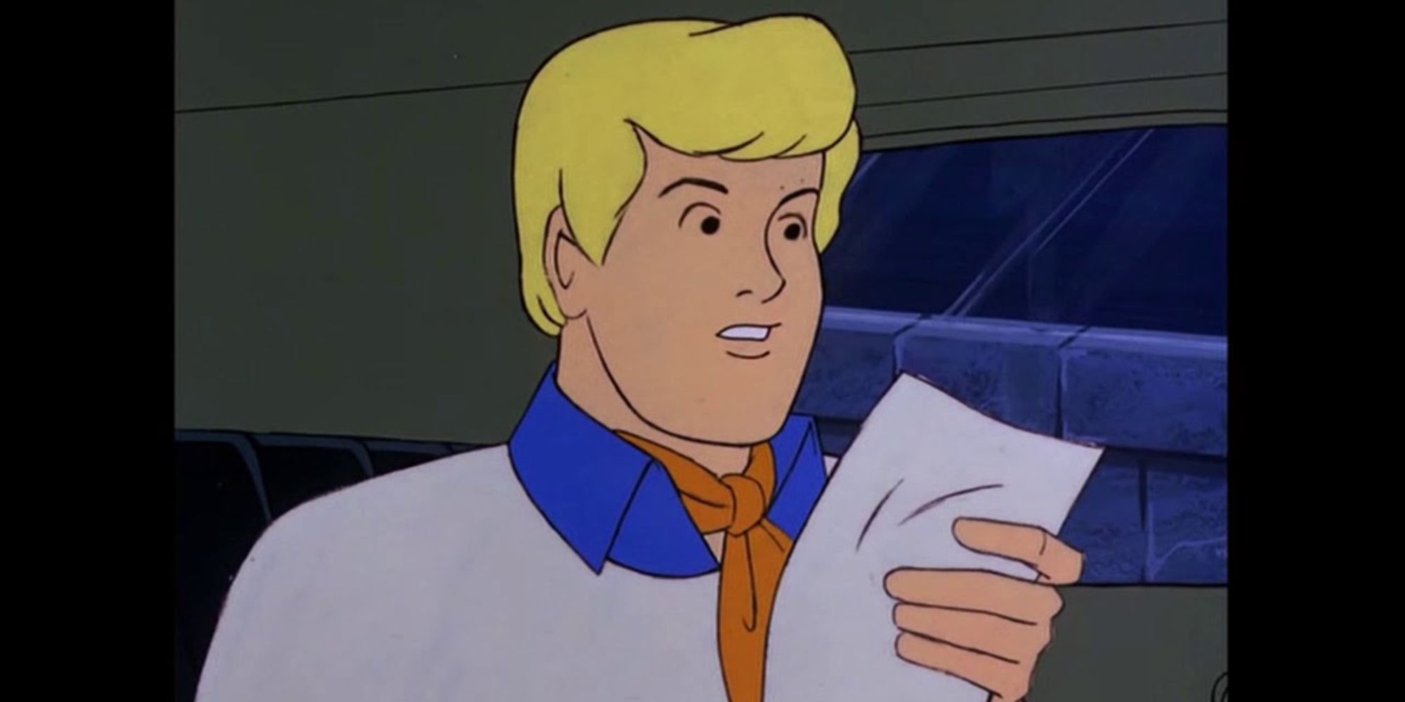Fred Jones looks at a piece of paper in Scooby-Doo