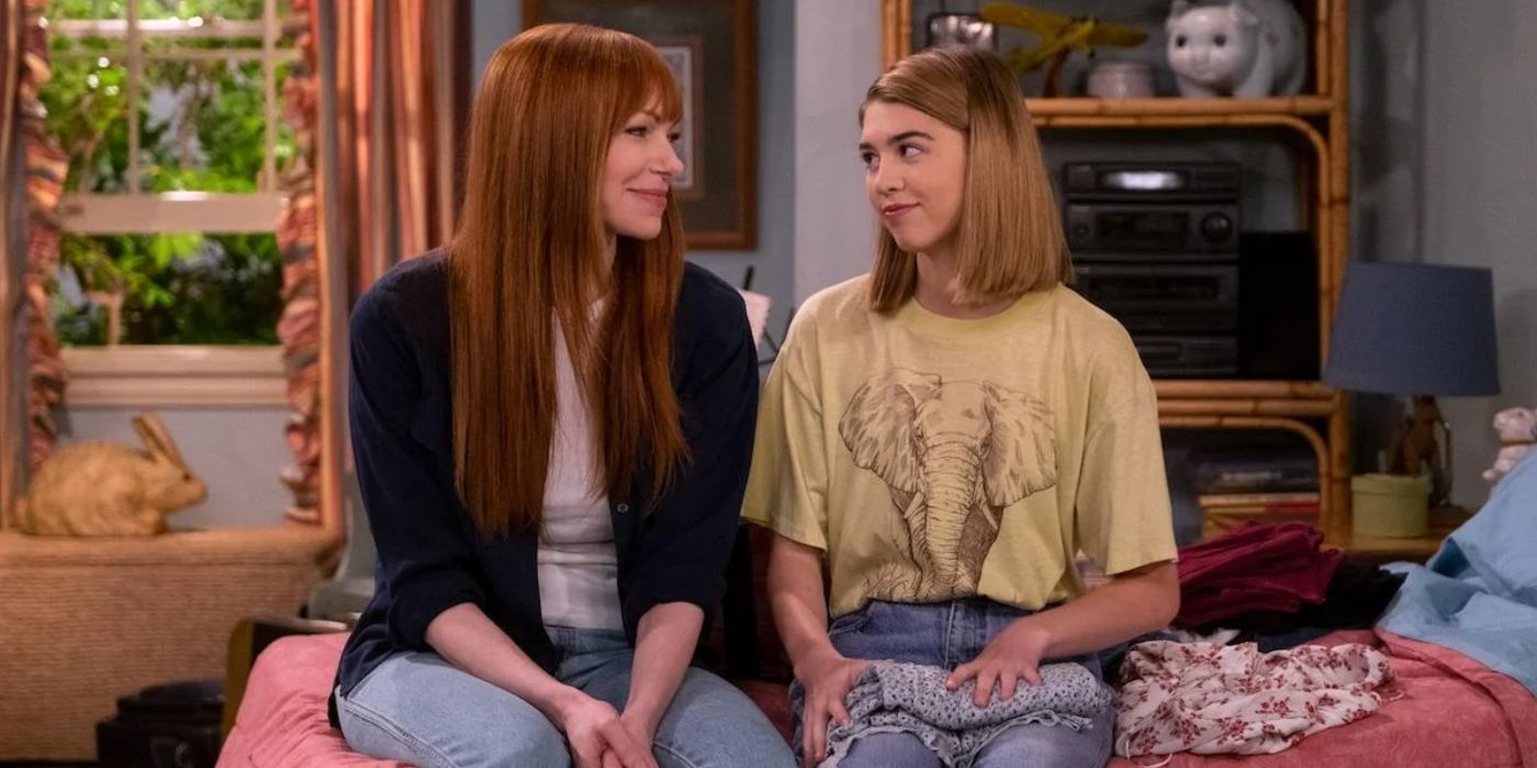 Donna and Leia sitting on a bed smiling at each other in That '90s Show. 