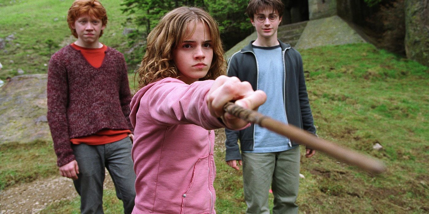 Hermione with wand pointed at screen while Ron and Harry Potter stand behind her
