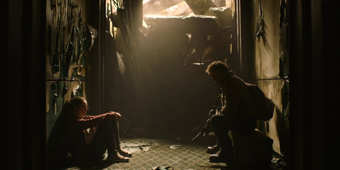 Joel and Ellie sit in a dark hall in The Last of Us 