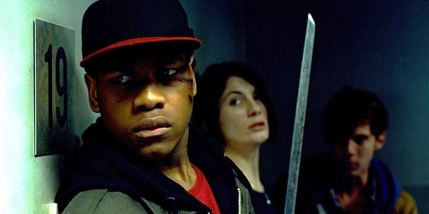 John Boyega holding a sword and looking off screen with two people behind him in Attack the Block