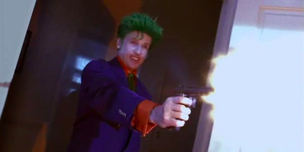 The Joker as seen in Birds of Prey fires a gun with a menacing smile