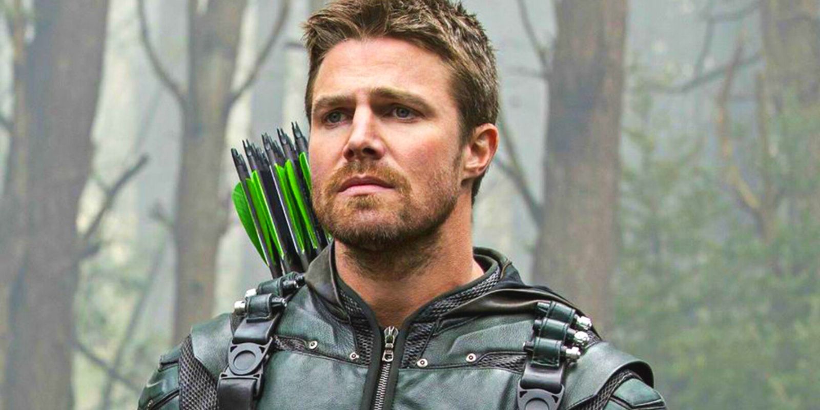 Green Arrow, played by Stephen Amell, stands in the woods