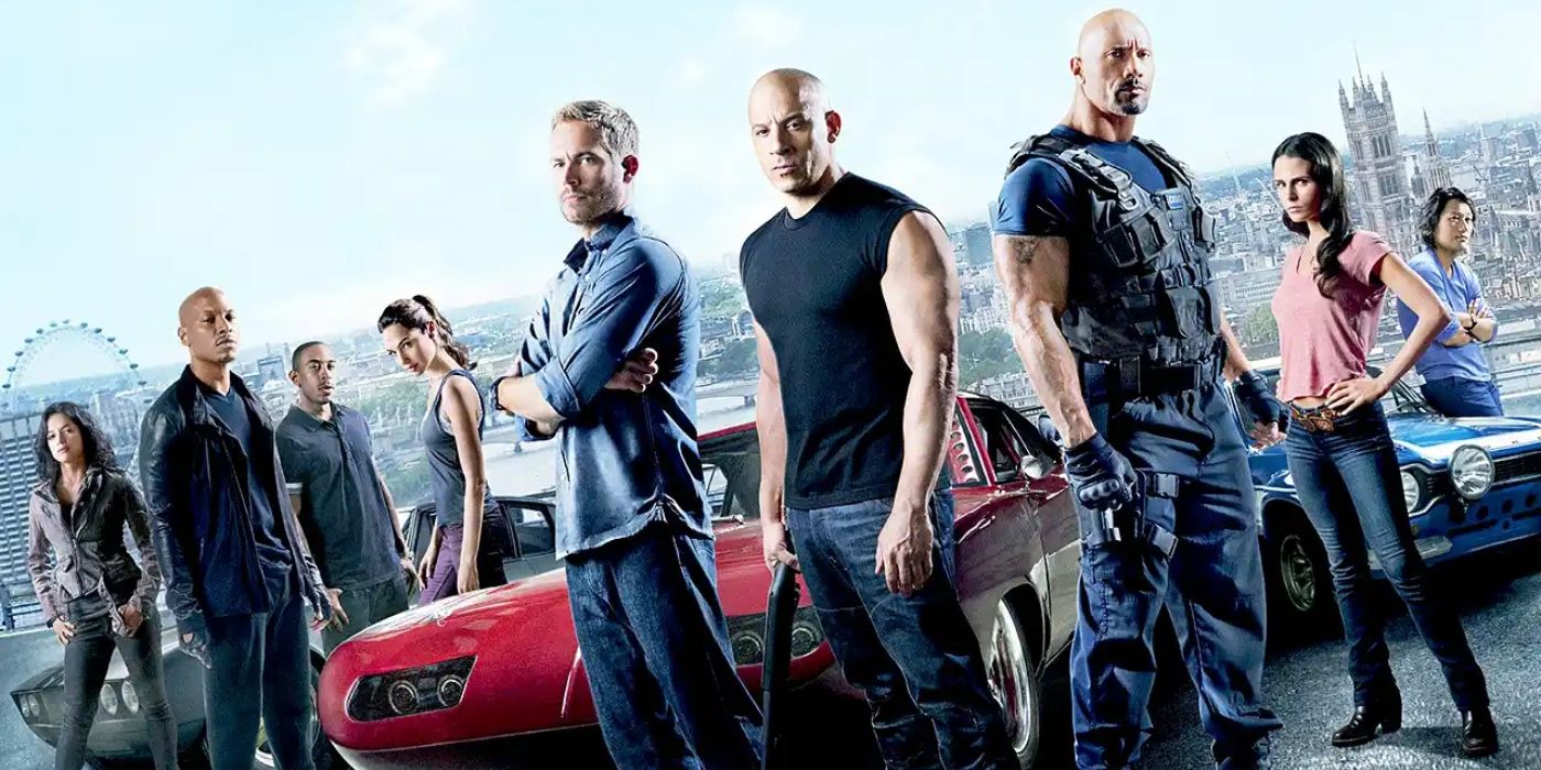 The cast of Fast & Furious 6 standing in front of cars.