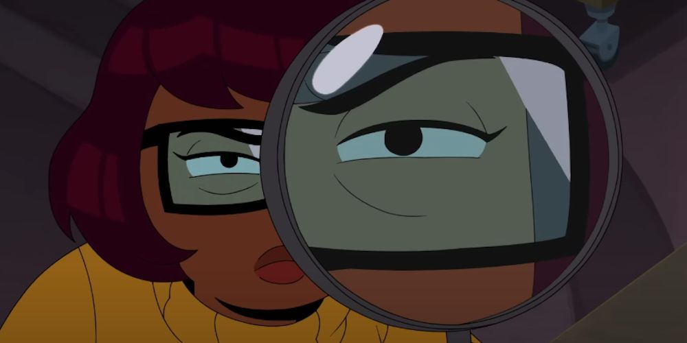 Velma looks at clues with a magnifying glass in Velma