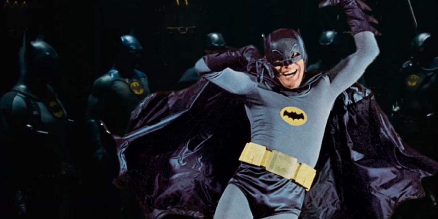 Adam West's Batman lies against a whole bunch of Bat Suits and laughs.