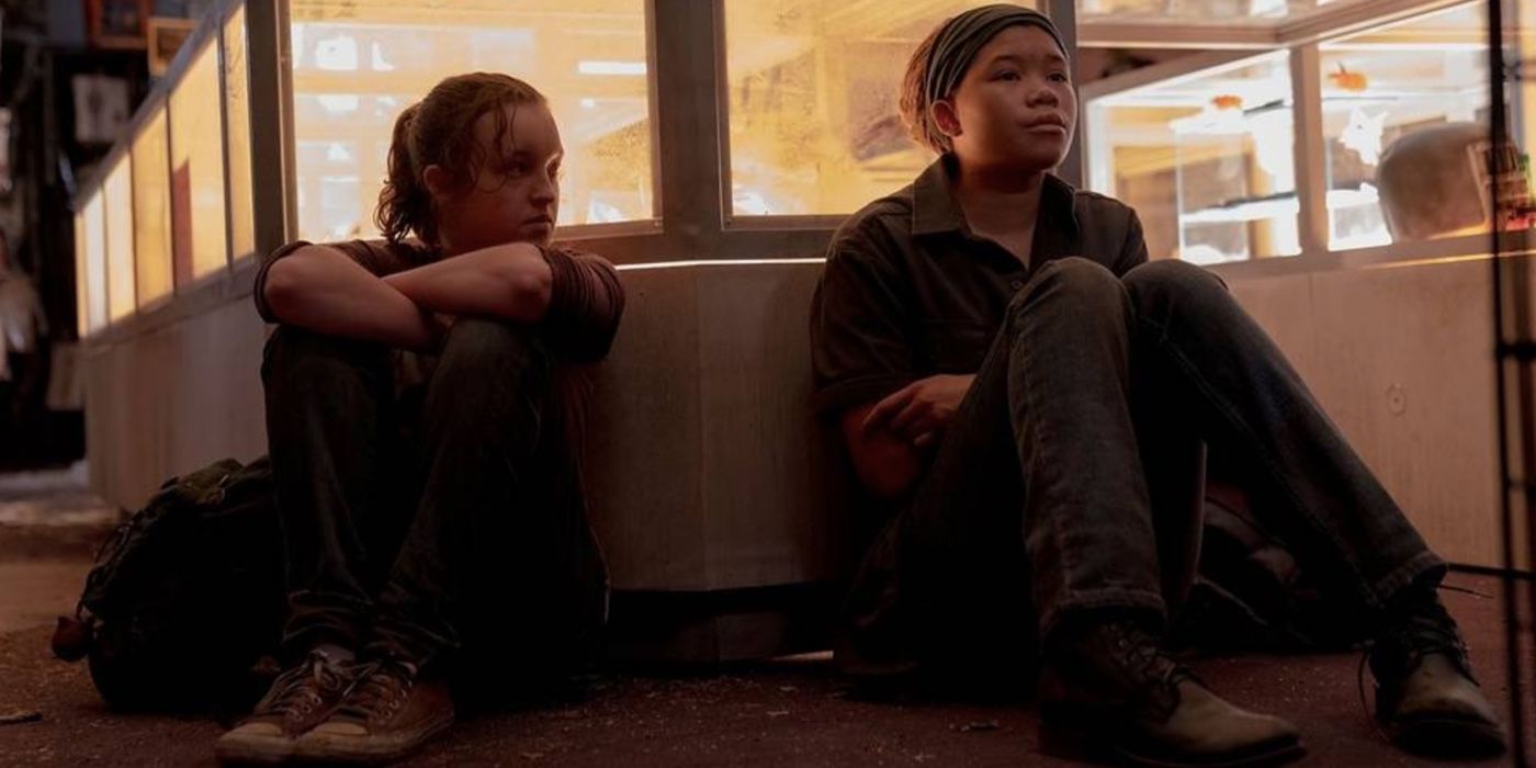 Riley e Ellie sentadas contra uma vitrine em The Last of Us