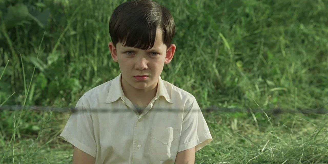A boy looks through a fence in The Boy in the Striped Pajamas 