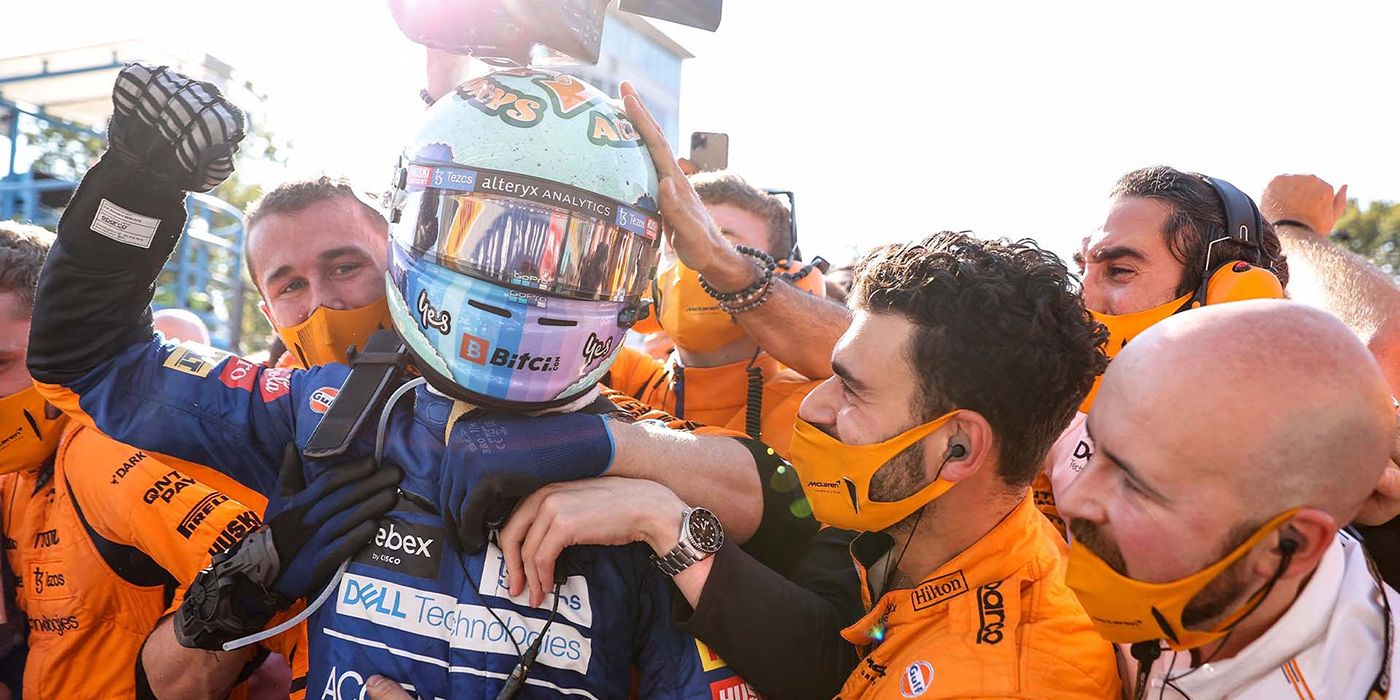 A race car driver raising his fist in celebration, others surrounding him in an image from Formula 1: Drive to Survive.