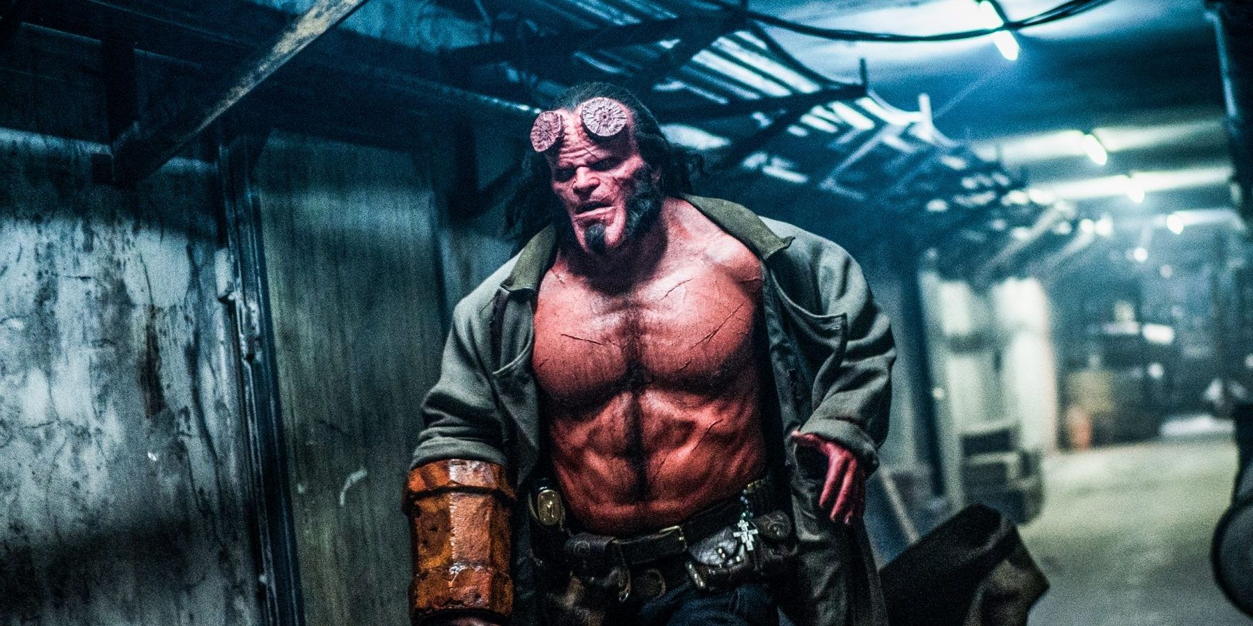 David Harbour, in full Hellboy makeup and costume, runs down a hallway.