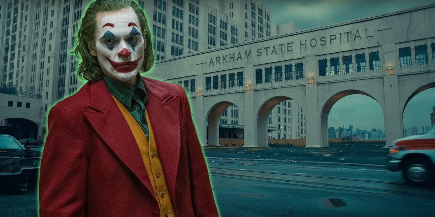 Joaquin Phoenix Joker in red suit with a green glow standing in front of Arkham State Hospital