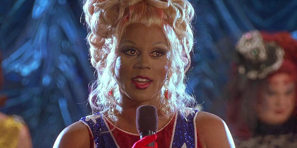 RuPaul como Rachel Tensions falando em um microfone em To Wong Foo.