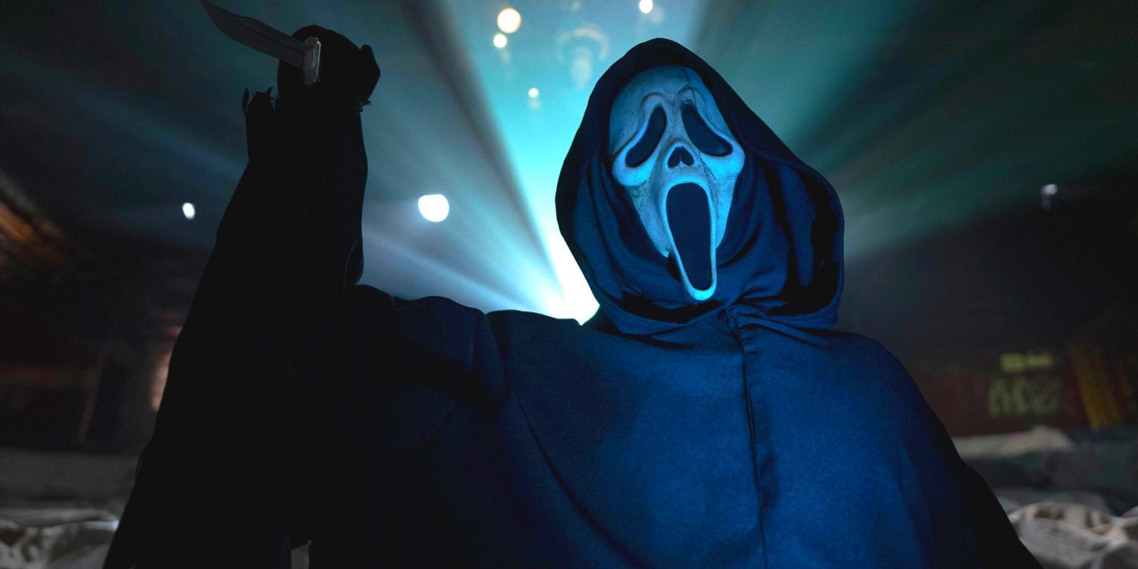 Ghostface em um cinema, segurando uma faca enquanto a luz do projetor brilha sobre ele