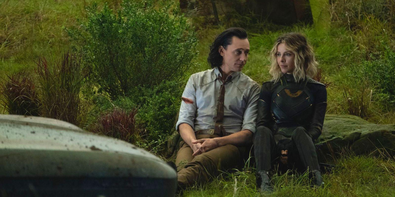 Loki and Sylvie sitting on a grassy mound in Loki TV show