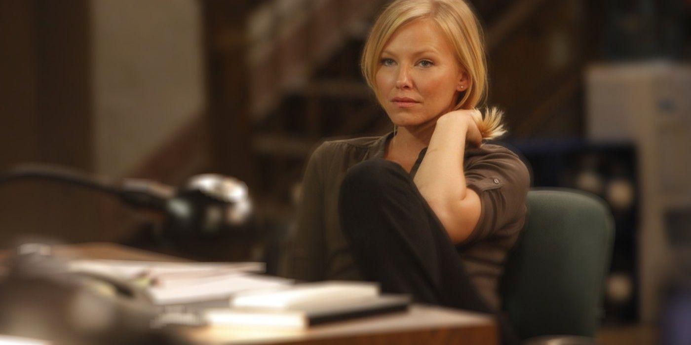 A blonde white woman, Kelli Giddish, sits at a desk in her portrayal of Law & Order's Amanda Rollins