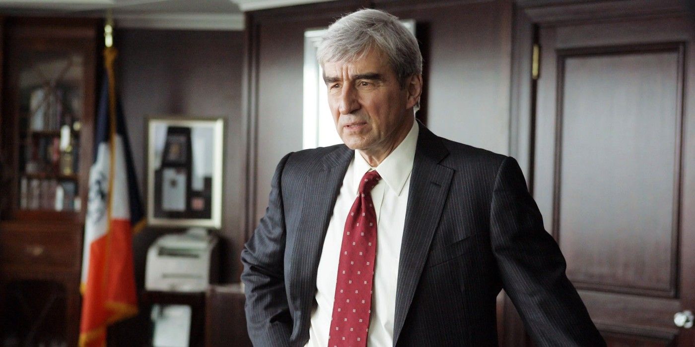 Sam Waterston as Jack McCoy leans on a desk with a hand on his hips in Law & Order. 