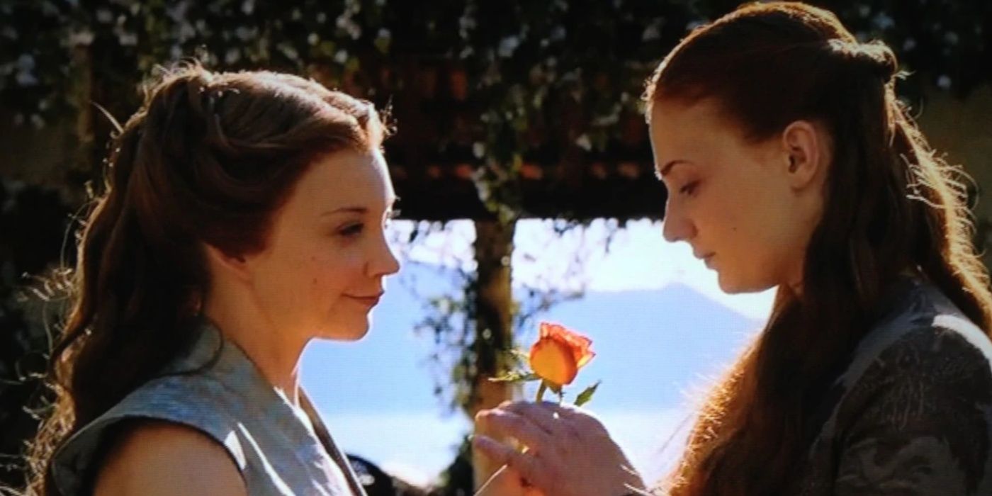 Margaery Tyrell handing Sansa Stark a flower in Game of Thrones. 