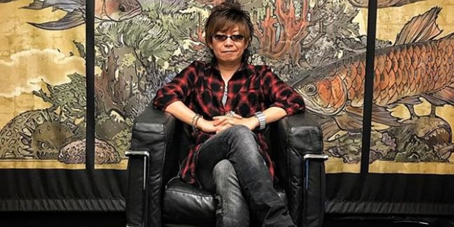 O desenvolvedor da Square Enix, Naoki Yoshida, está sentado em uma cadeira.