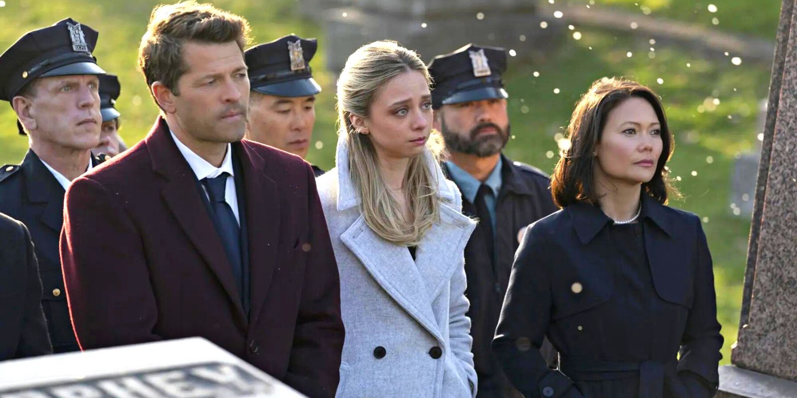 Misha Collins' Harvey Dent alongside Anna Lore's Stephanie Brown at a funeral, backed by police officers