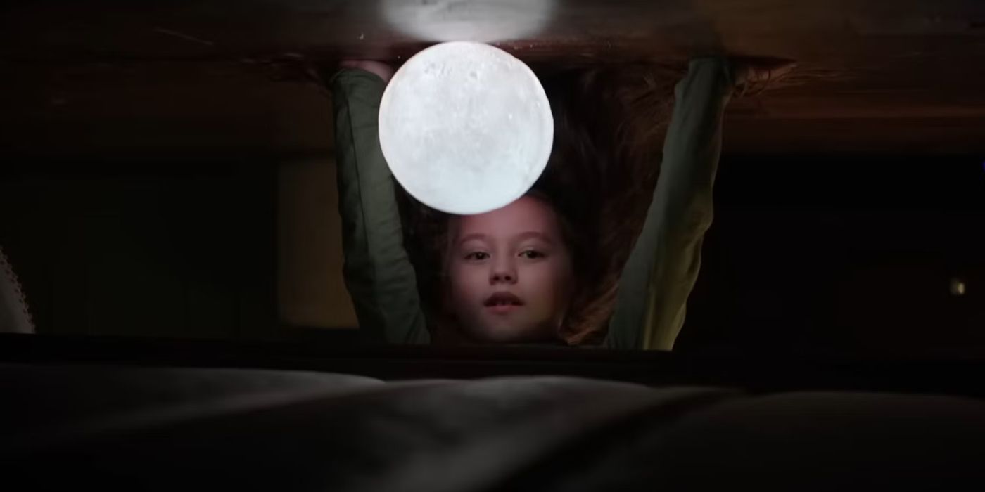 Sawyer (played by actor Vivien Lyra Blair) looks under her bed at a ball of light in The Boogeyman
