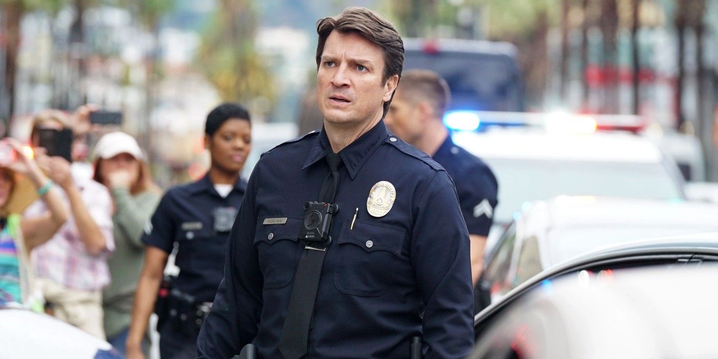 Nathan Fillion stands in front of a police car in ABC's The Rookie. 