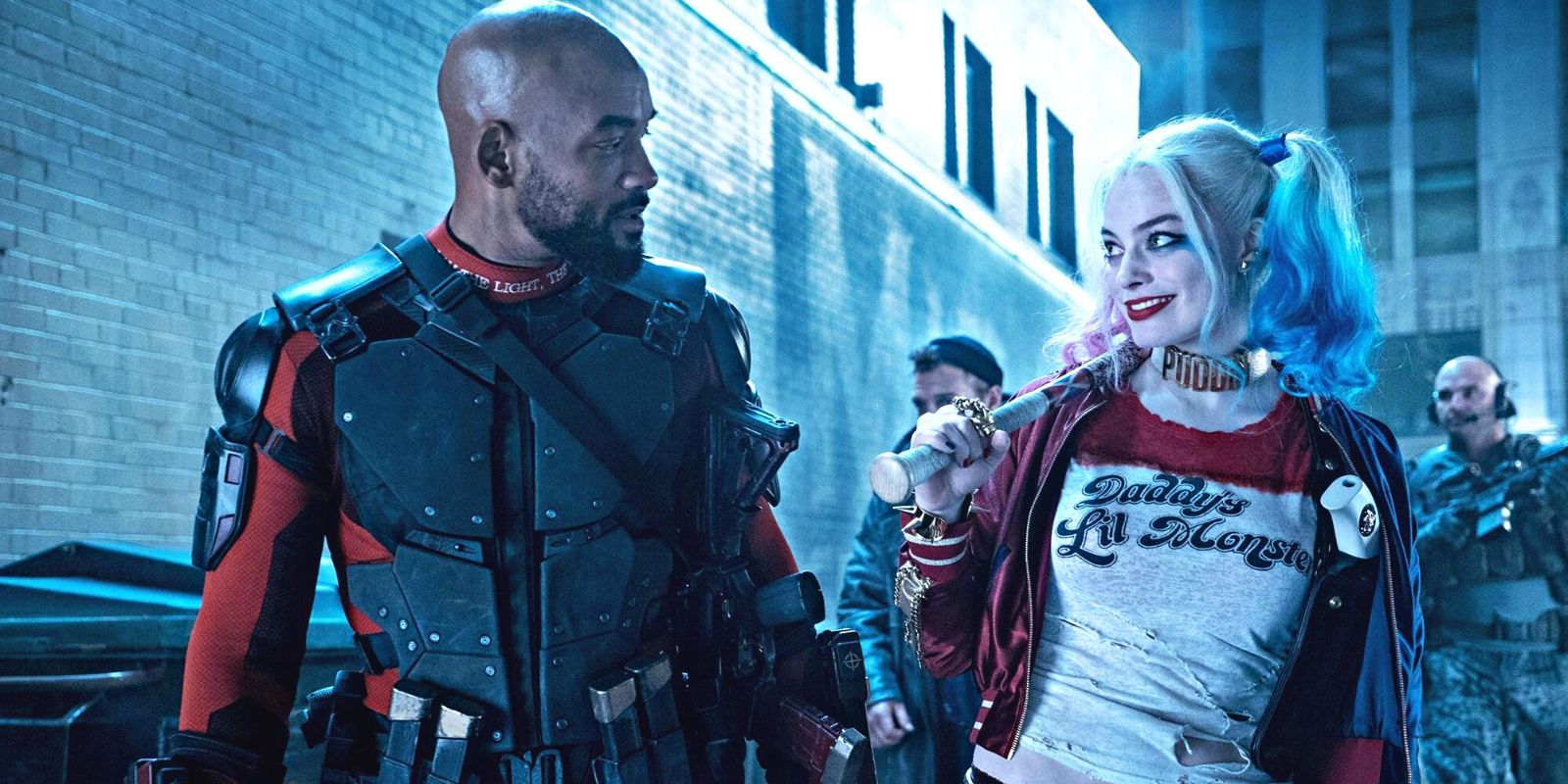 Deadshot and Harley Quinn share a cheeky smile in a dark alley in Suicide Squad