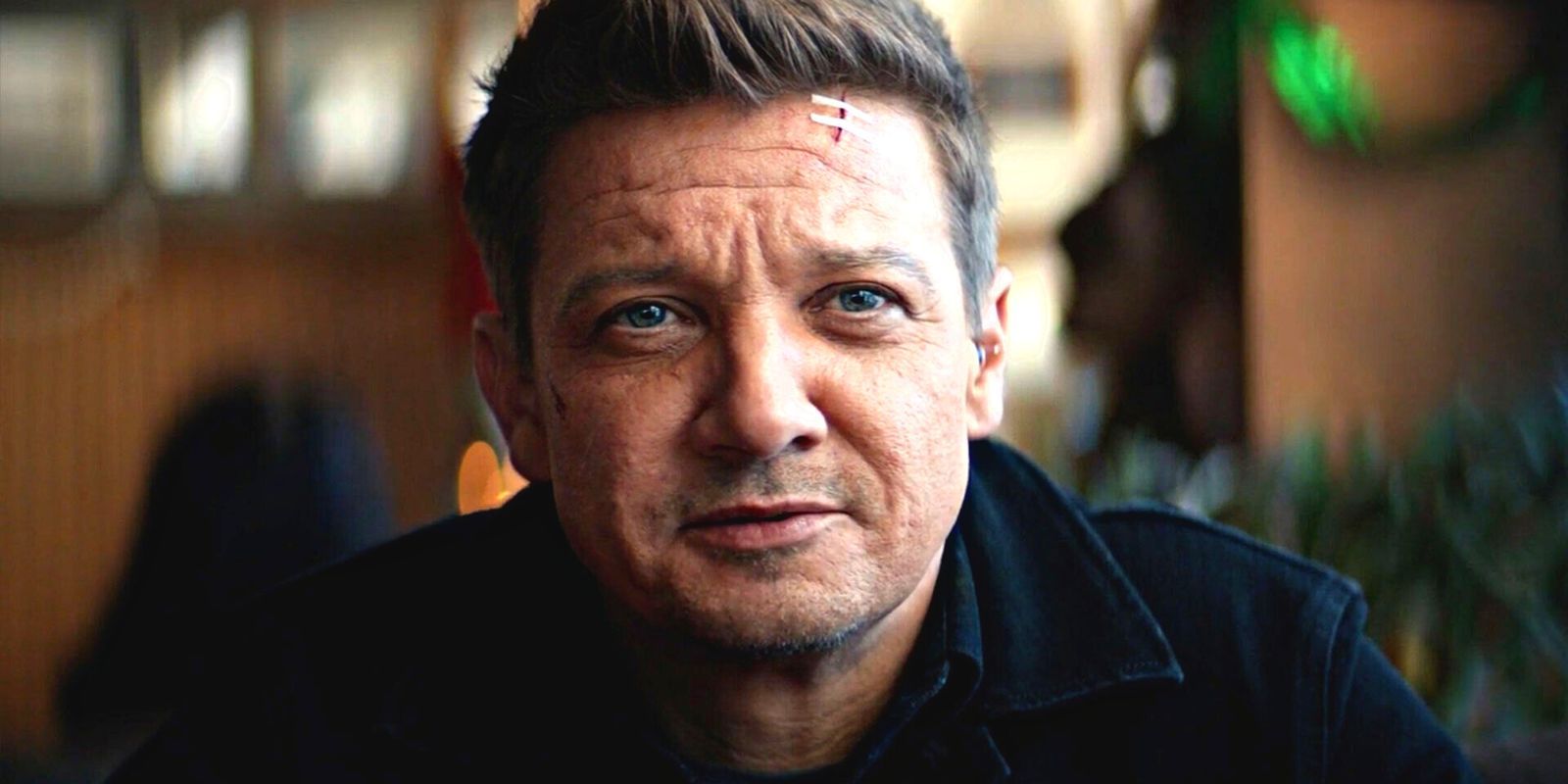 Jeremy Renner with two band-aids on his forehead over a nasty cut