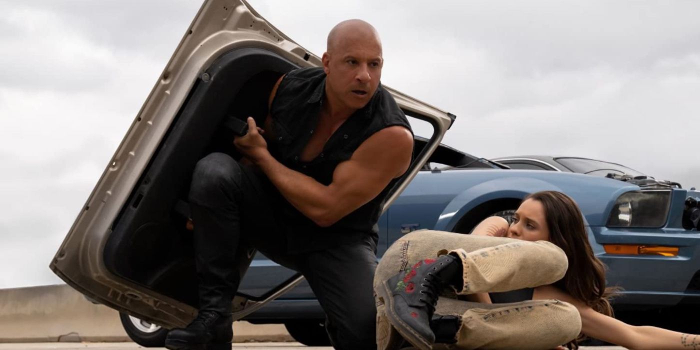 Vin Diesel's Dom Toretto holding a car door like a shield over Daniela Melchior's Isabel in Fast X.