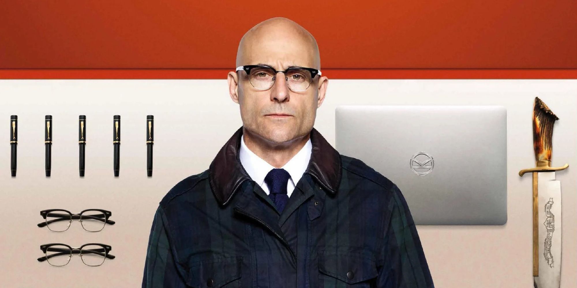 Kingsman's Merlin, played by Mark Strong, standing in front of a wall of Kingsman tech.