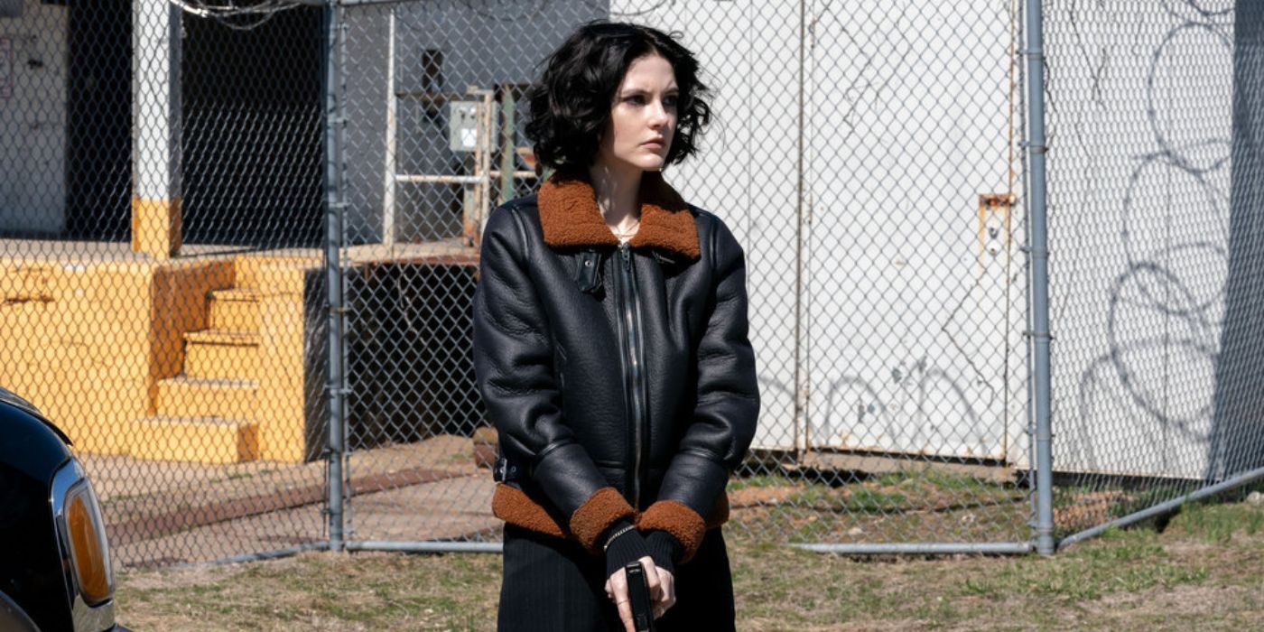 Law & Order: Organized Crime's Jet (Ainsley Seiger) holds a gun in a leather jacket outside a house