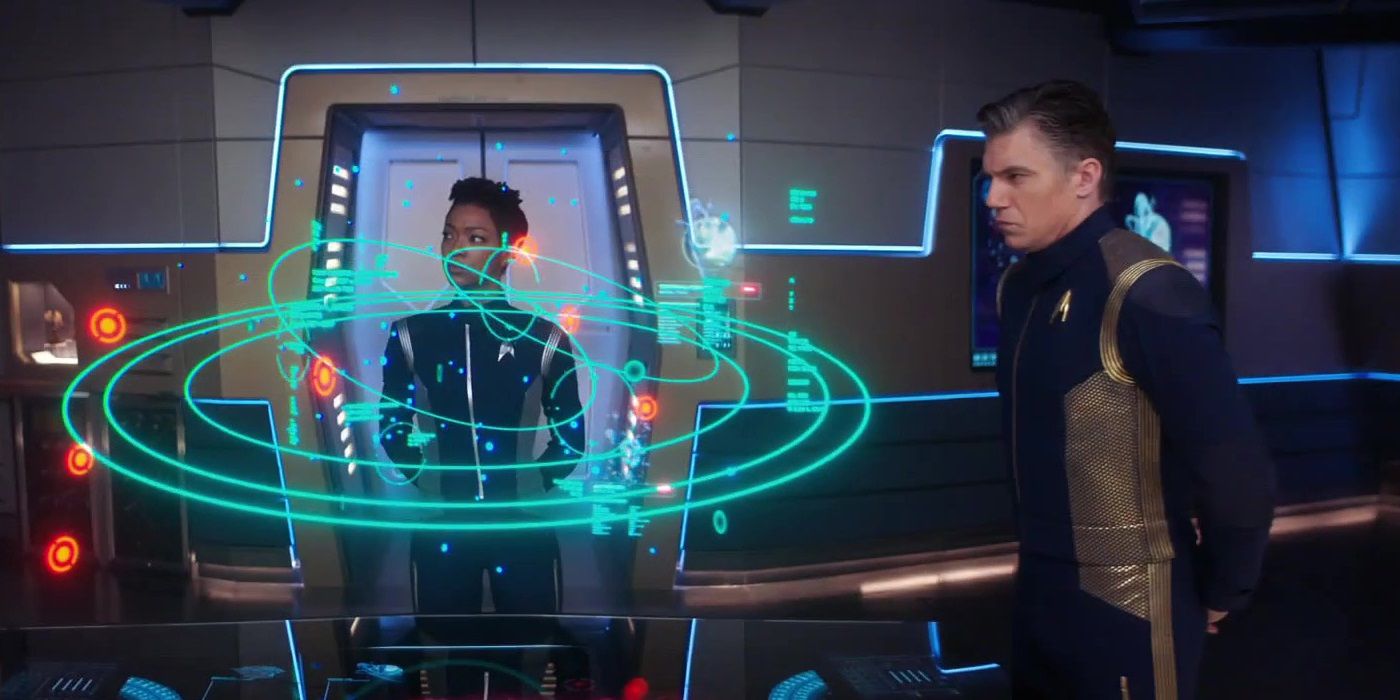 Star Trek Discovery Michael Burnham and Captain Pike in blue jumpsuits looking at a hologram map of the galaxy