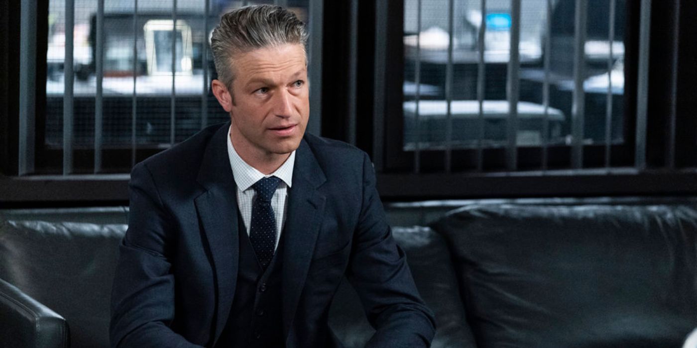 Law & Order: ADA Sonny Carisi (Peter Scanavino) da SVU está sentado em um sofá em um terno preto