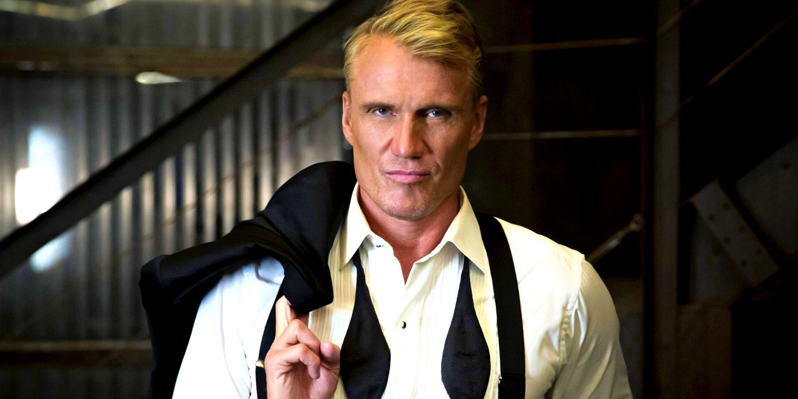 Dolph Lundgren in a tuxedo with his jacket draped over his shoulder and the bowtie undone