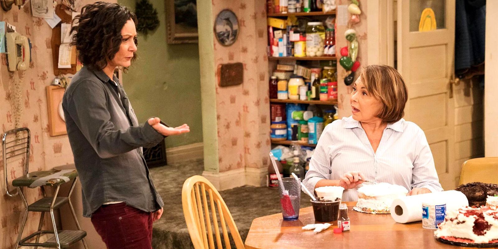 Sara Gilbert and Roseanne Barr standing in a kitchen having a discussion