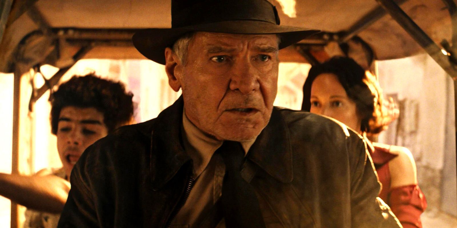 A concerned Indiana Jones flanked by two people in the back of a rickshaw