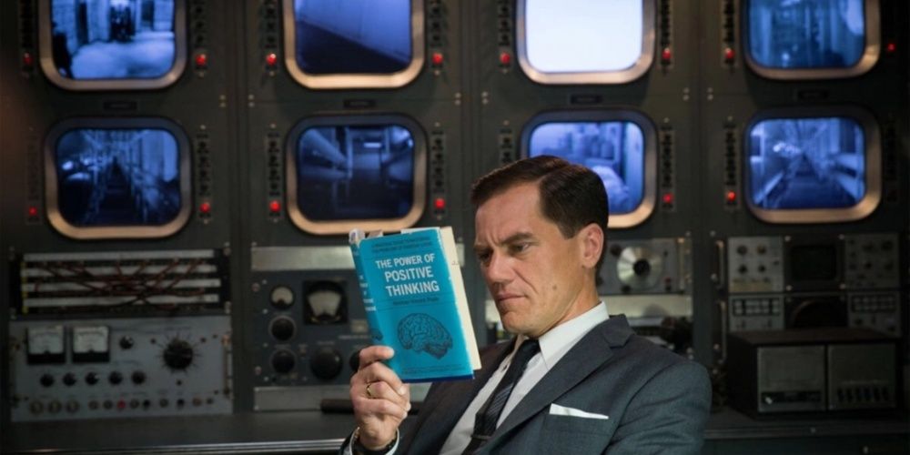 El coronel Richard Strickland de Michael Shannon lee un libro frente a los monitores (La forma del agua)