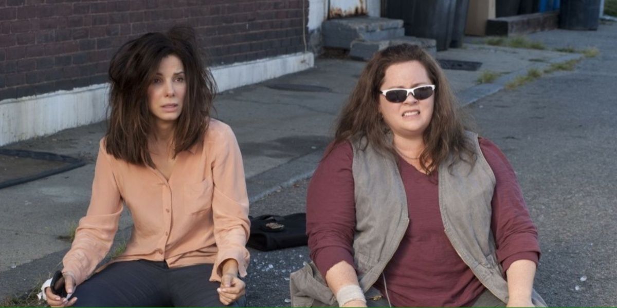 Sandra Bullock y Melissa McCarthy en The Heat sentadas en la acera.