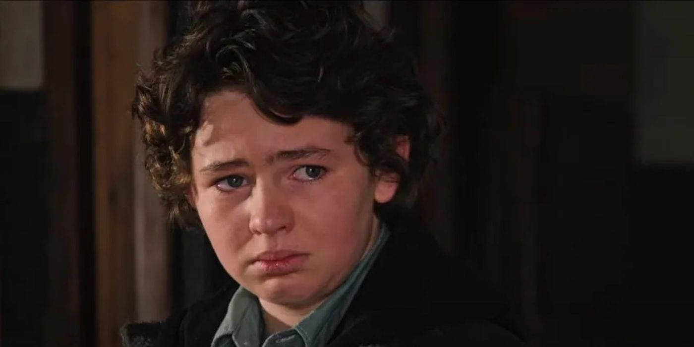 Carter (Finn Little) looks sad and tears up while standing in the barn on Yellowstone.