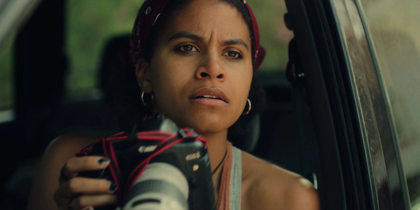 Bo (Zazie Beetz) está sentada em seu carro e segura sua câmera enquanto olha para uma celebridade que deseja fotografar.