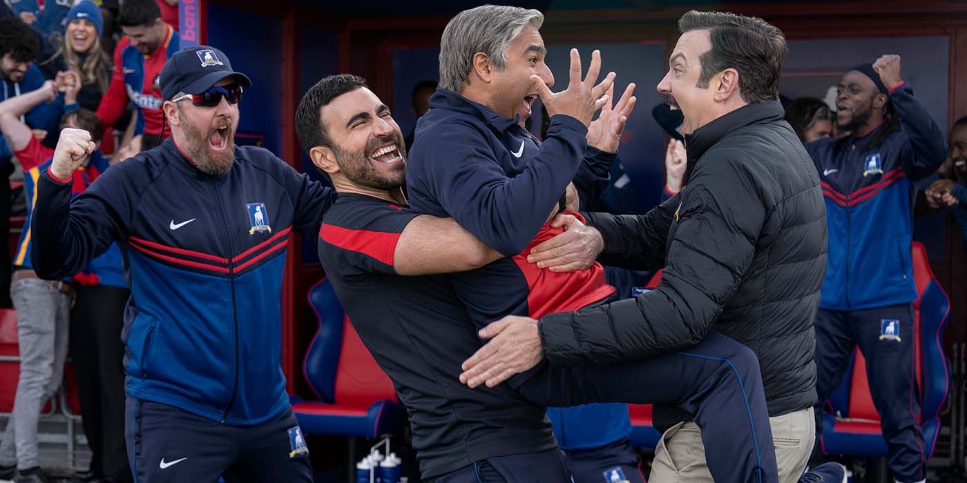 Beard torcendo, com Roy Kent e Ted Lasso segurando Nathan Shelley após a grande vitória do AFC Richmond. 