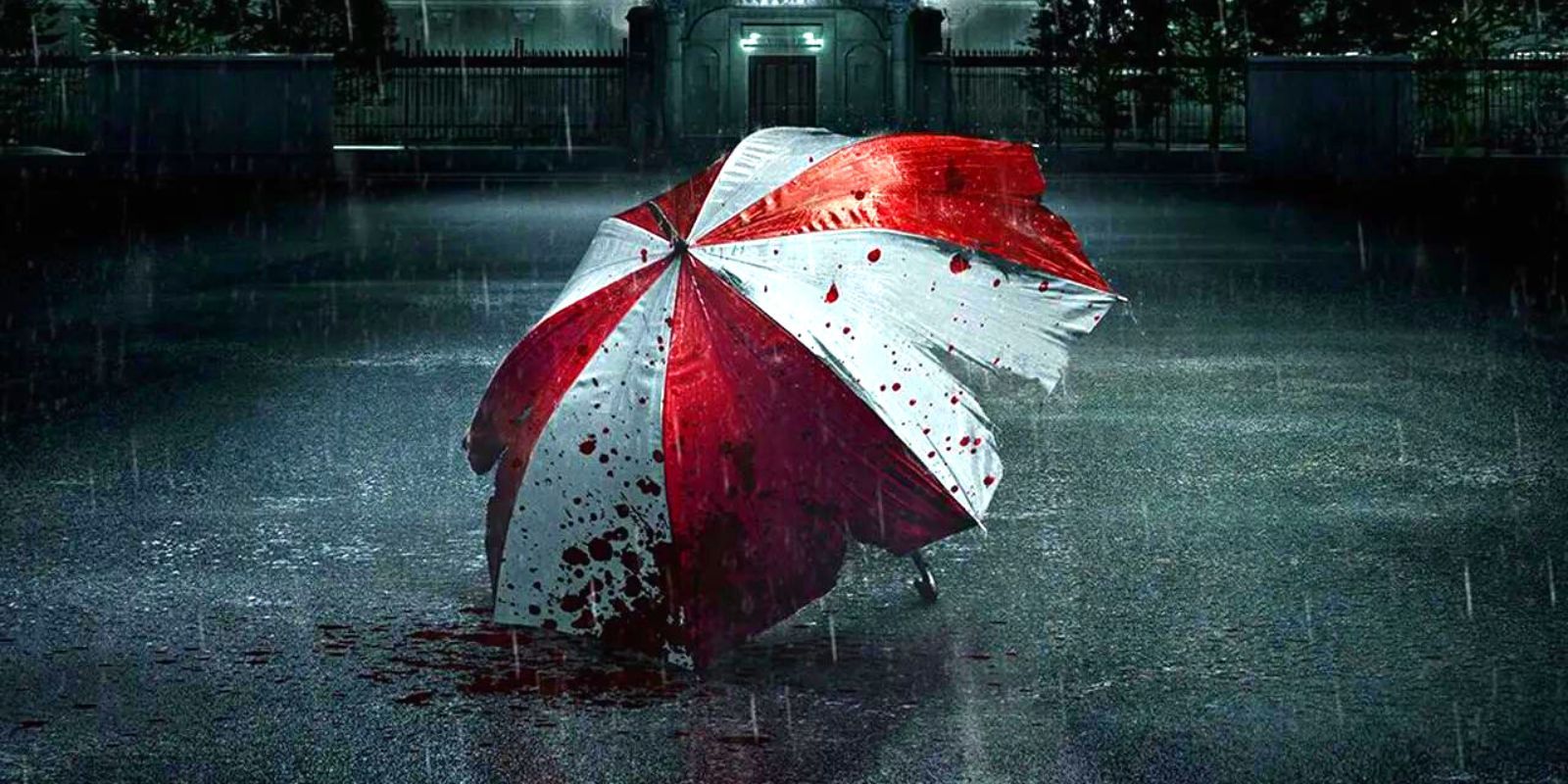 A red and white umbrella stained with blood lying in a rain-soaked road