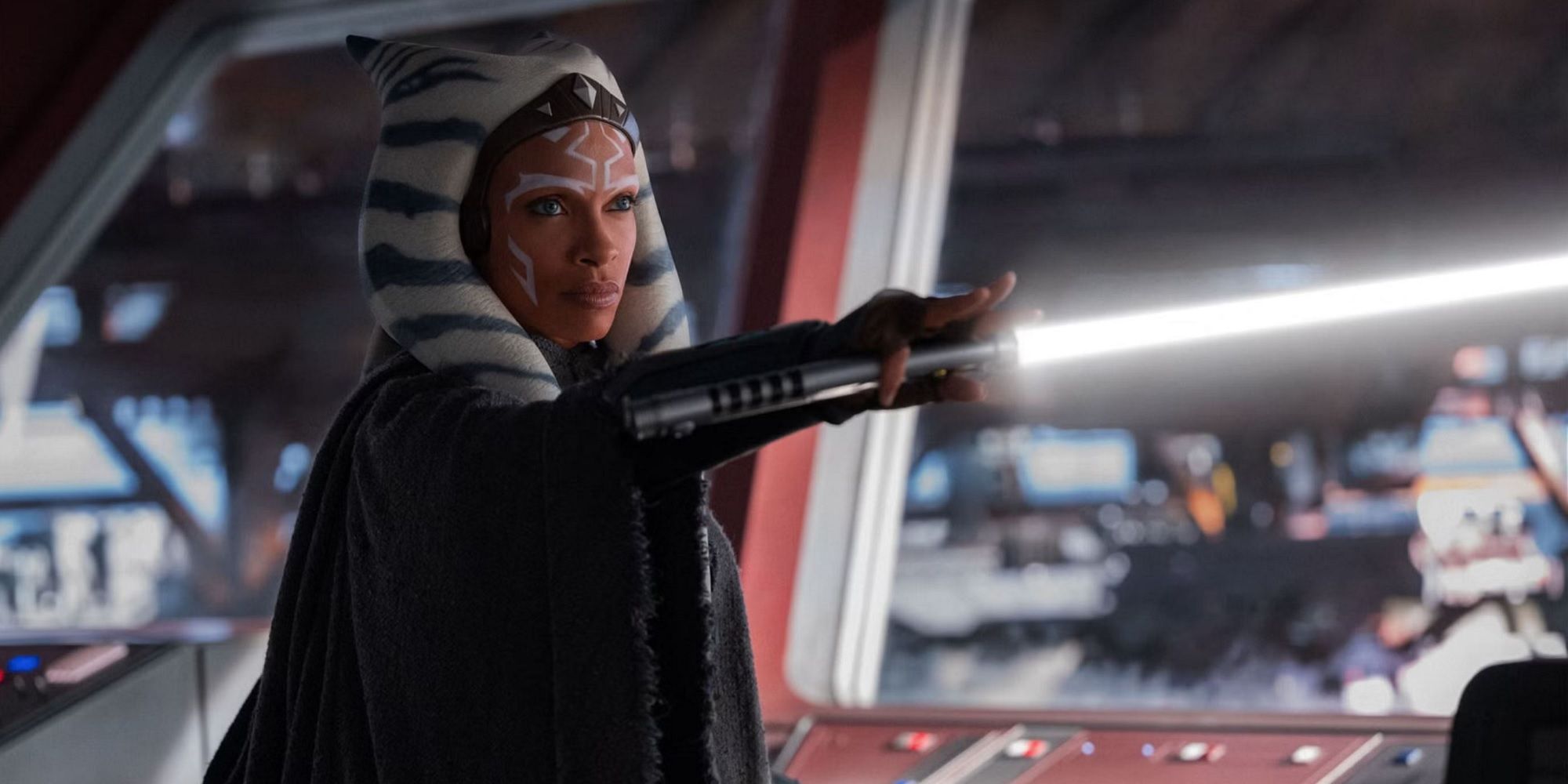 Ahsoka Tano (played by actor Rosario Dawson) points a white lightsaber inside a spaceship