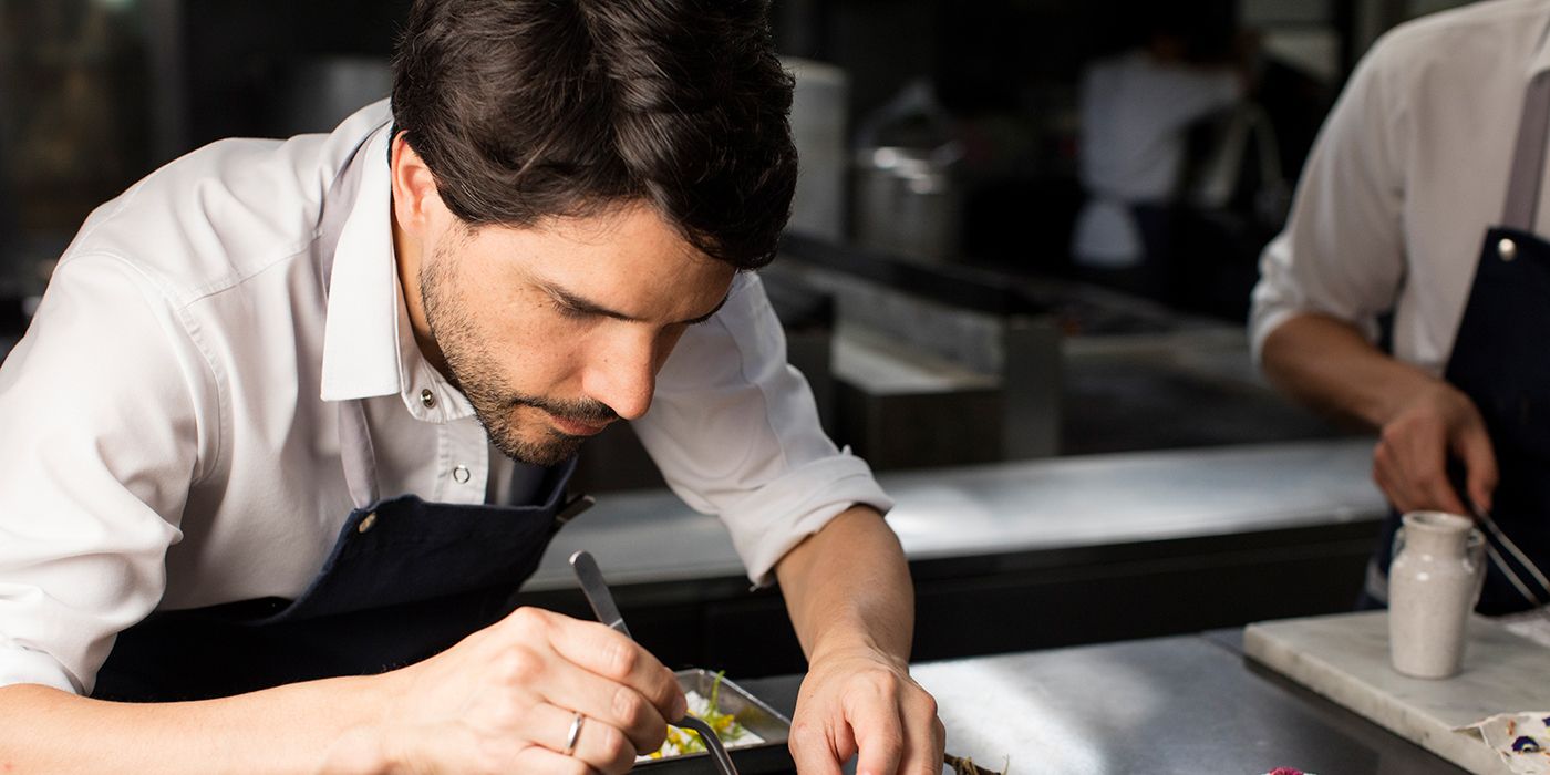 Um chef trabalhando intensamente em um prato em uma cena de Chef's Table.