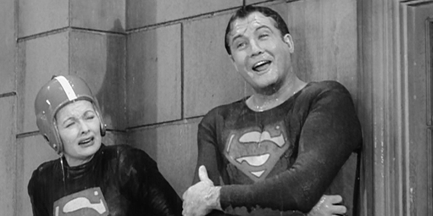 Lucy and George Reeves stand on a ledge in the rain as Reeves cracks a joke in I Love Lucy, Lucy and Superman