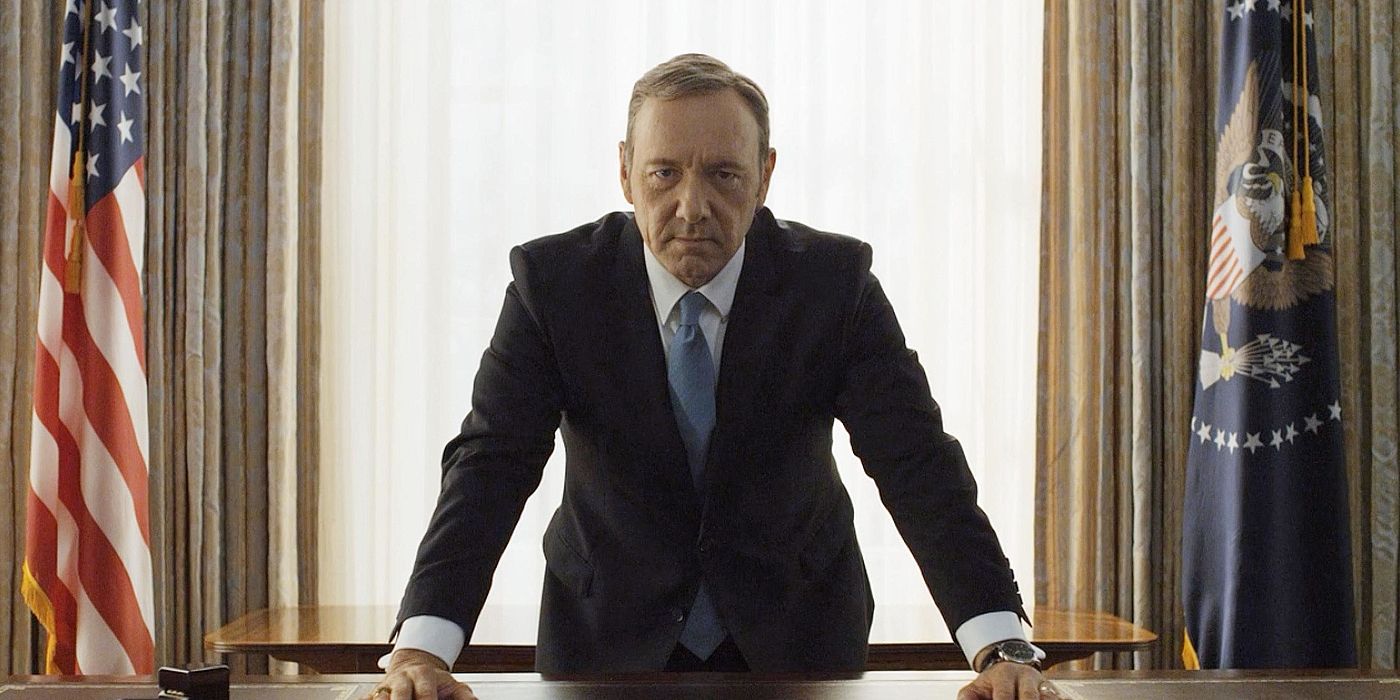 Kevin Spacey, who played Francis J. Underwood on House of Cards, is standing with his hands on the desk