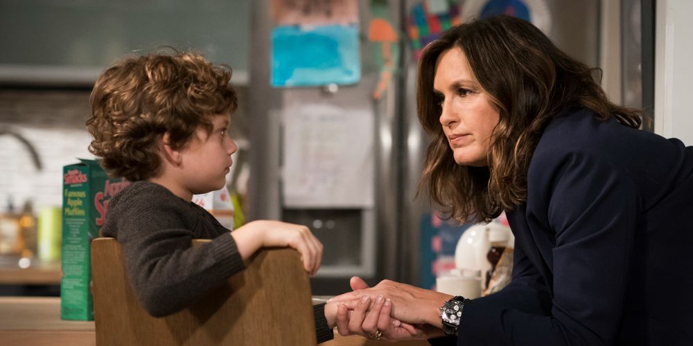 Noah Porter-Benson, played by Ryan Buggle, sits with Olivia Benson, played by Mariska Hargitay, in their kitchen on Law & Order: SVU.