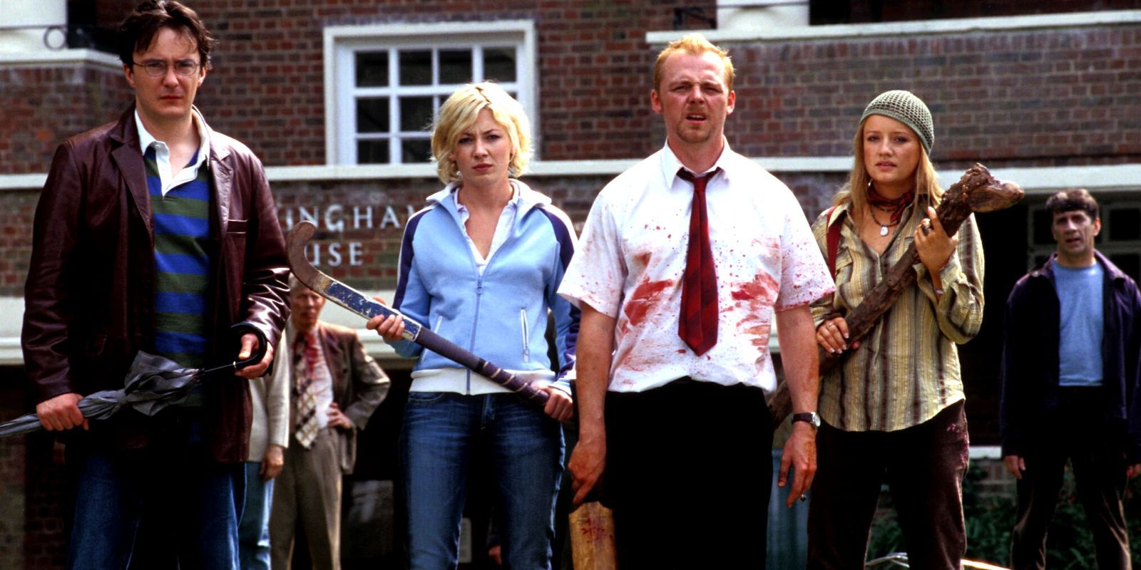 O elenco de Shaun of the Dead parado na rua com as armas