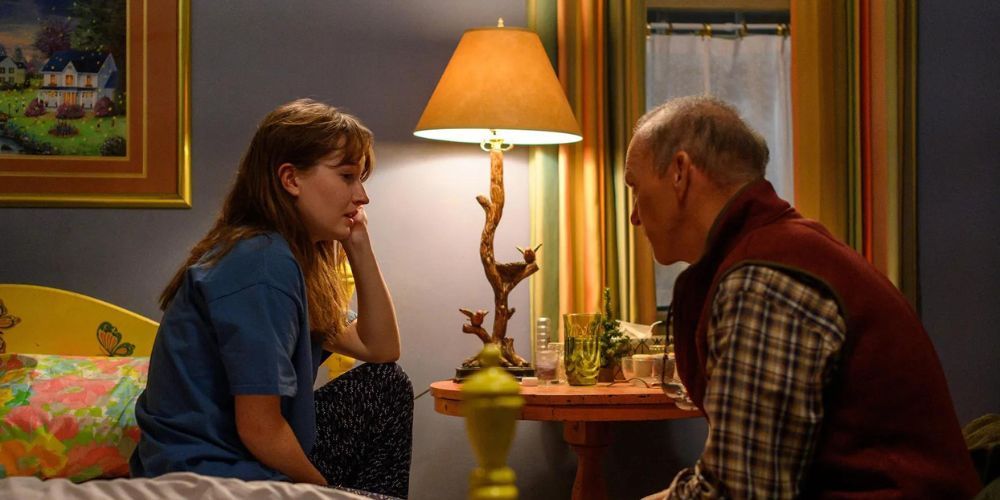 Kaitlyn Dever como Betsy Mallum sentada em sua cama em seu quarto em frente a Michael Keaton como Dr. Samuel Finnix em Dopesick