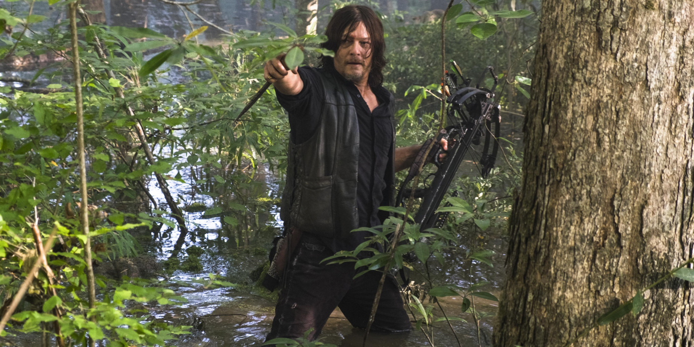 Daryl Dixon (Norman Reedus) pointing forward in a swamp on The Walking Dead