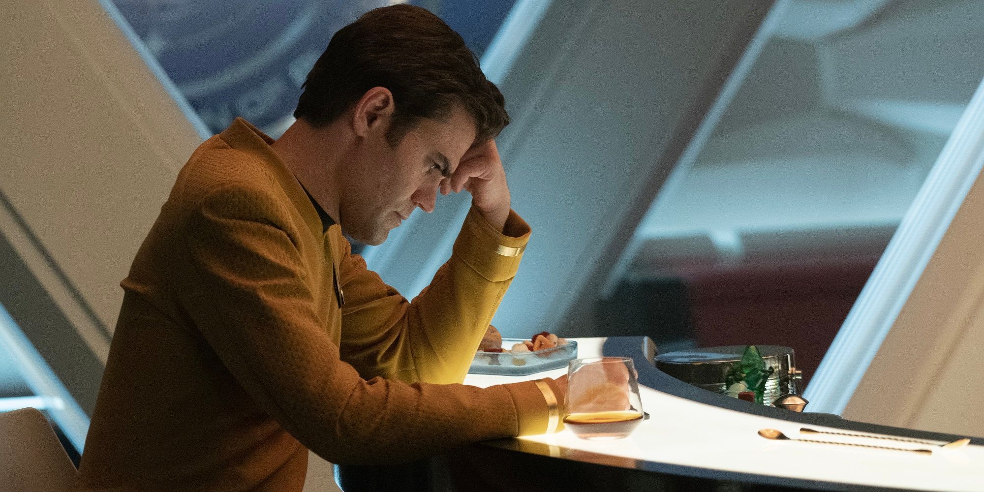 James T. Kirk sitting in the Enterprise lounge, looking down on Star Trek: Strange New Worlds